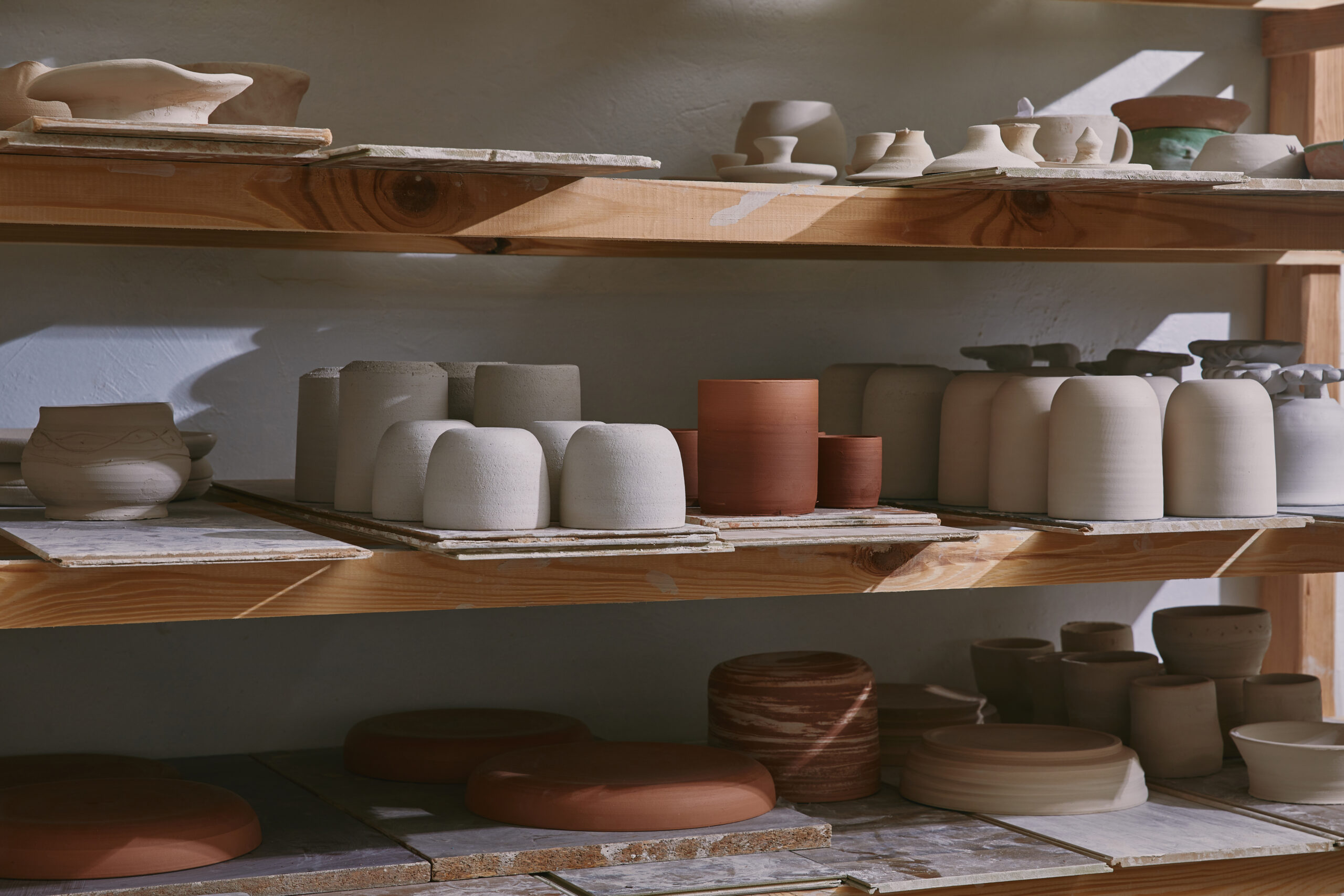 ceramic bowls and dishes on wooden shelves at pottery studio